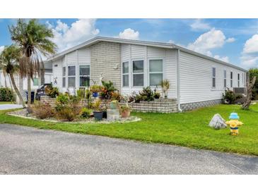 White single-wide manufactured home with landscaped yard and carport at 472 Sharks Pt, North Port, FL 34287