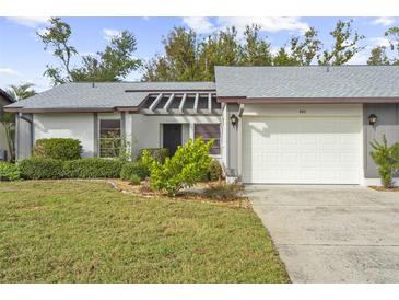 Charming condo with gray roof, white garage door, and well-manicured lawn at 605 Apple Ln, Englewood, FL 34223