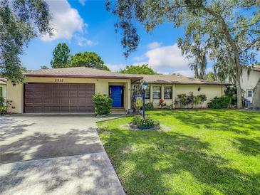 Single story home with brown garage door, blue front door, and well-manicured lawn at 2512 Regatta Dr, Sarasota, FL 34231