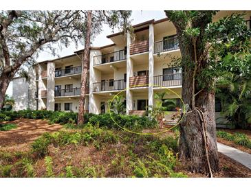 Condo building exterior with lush landscaping and walkway at 1174 Bird Bay Way # 107, Venice, FL 34285