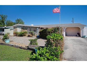 Ranch-style home with stone accents, mature landscaping, and a flag at 126 Venice East Blvd, Venice, FL 34293
