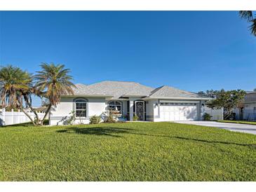 Single-story home with white garage door, and palm trees, on a large grassy lot at 30 Princeton Rd, Venice, FL 34293