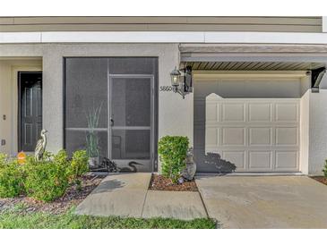 Exterior view of house featuring a screened-in door, garage, and landscaping at 5860 Ocean Isle Dr, Nokomis, FL 34275