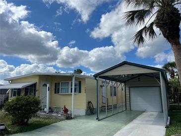 Yellow single-wide mobile home with carport and landscaping at 782 Londra Dr, Venice, FL 34285