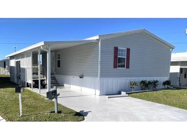 Mobile home with carport, landscaped yard, and gray siding at 334 Blackburn Blvd, North Port, FL 34287