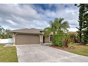 Tan house with attached garage, landscaping, and palm trees at 23102 Madelyn Ave, Port Charlotte, FL 33954