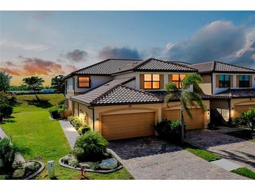 Attractive two-story townhome with tile roof, paver driveway, and attached two-car garage at 20100 Ragazza Cir # 101, Venice, FL 34293