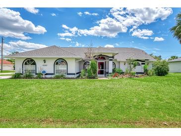 Single-story home with a large front yard, mature landscaping, and a two-car garage at 23167 Turnbull Ave, Port Charlotte, FL 33954