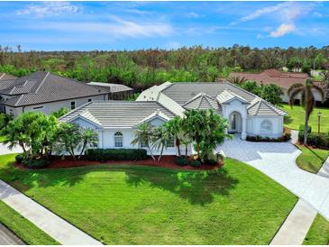 Aerial view of a single-story home with tile roof, lush landscaping, and paved driveway at 4151 Natale Dr, Venice, FL 34293