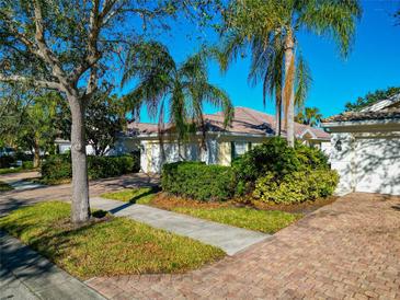 Attractive single-story home with a two-car garage, brick driveway, and lush landscaping at 5856 Helicon Pl, Sarasota, FL 34238