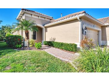 Tan house with tile roof, landscaping, and a two-car garage at 11539 Okaloosa Dr, Venice, FL 34293