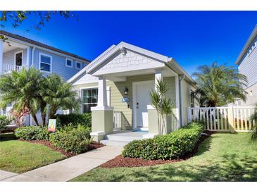 Charming green house with a landscaped front yard and white picket fence at 12681 Sagewood Dr, Venice, FL 34293