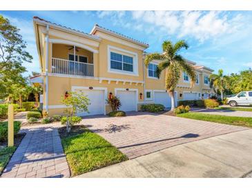 Tan townhouses with white garage doors, paved driveways, and palm trees at 128 Navigation Cir # 103, Osprey, FL 34229