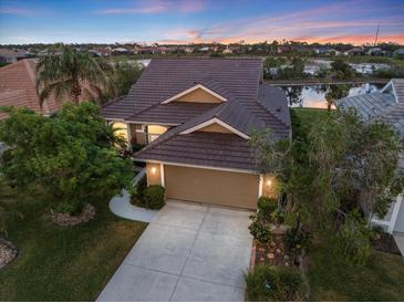 Charming home with tile roof, attached garage, and landscaped yard at sunset at 1307 Highland Greens Dr, Venice, FL 34285