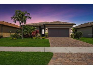 Beautiful single-story home features a well-manicured lawn and a brick driveway leading to an attached two-car garage at 13510 Esposito St, Venice, FL 34293
