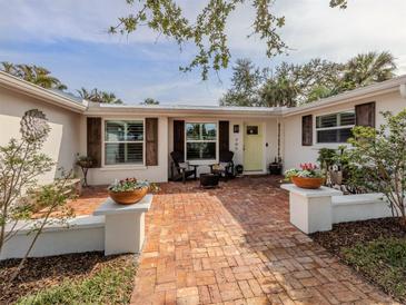Charming home entrance with brick walkway, decorative flower pots, and inviting outdoor seating area at 705 Armada N Rd, Venice, FL 34285