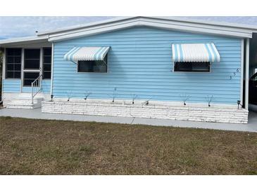 Charming blue home featuring awnings and well-maintained front yard with garden feature at 356 Longwood Dr, Venice, FL 34285