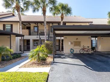 Condo building featuring a carport, palm trees, and lush landscaping in a well-maintained community at 380 Three Lakes Ln # F, Venice, FL 34285