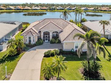 Stunning single-story home with a tile roof, lush landscaping, and a serene waterfront view at 1374 Brenner Park Dr, Venice, FL 34292