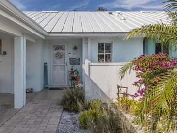 Charming front entrance with white picket fence and lush tropical foliage create inviting curb appeal at 335 Englewood Isles Pkwy # 55, Englewood, FL 34223