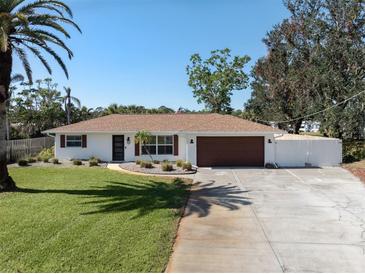 Charming single-story home with a well-manicured lawn, mature palm trees, and a driveway leading to an attached garage at 809 Garland Ave, Nokomis, FL 34275