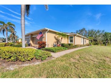 A charming home with a well-manicured lawn, lush landscaping, and a quaint walkway, with a prominent American flag display at 13542 Abercrombie Dr, Englewood, FL 34223