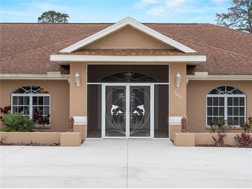 Charming front entrance with decorative dolphin screen doors and manicured landscaping at 1611 Thomas St, Englewood, FL 34223