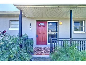 Charming home entrance with a vibrant red door, patterned tile, and inviting curb appeal at 7903 Hyde Park Ave, North Port, FL 34287