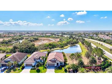 Stunning aerial view of home with tile roof situated on a lush lot with a pond view and mature landscaping at 351 Carlino Dr, Nokomis, FL 34275