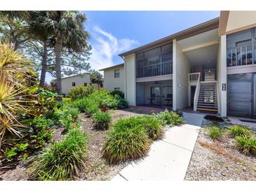 Well maintained condo building with mature landscaping, including vibrant flowers and lush greenery near the entrance at 638 Bird Bay E Dr # 201, Venice, FL 34285