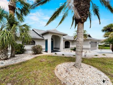 Charming single-story home featuring a well-manicured lawn, blue door, and tasteful landscaping with palm trees at 8 Bunker Ln, Rotonda West, FL 33947