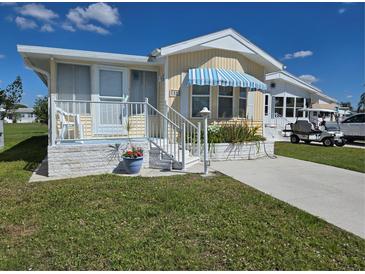 Charming single-Gathering home with a well-manicured lawn and a blue striped awning at 88 Bainbridge Dr # 88, Nokomis, FL 34275