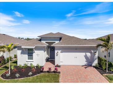 Charming single-Gathering home featuring a manicured lawn and two-car garage, complete with a brick paver driveway at 16131 Poplar Hill Ln, Port Charlotte, FL 33953