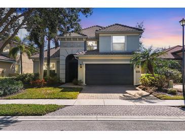Two-story home featuring a well-maintained lawn, gray facade, tile roof, and attached two-car garage at 23138 Copperleaf Dr, Venice, FL 34293