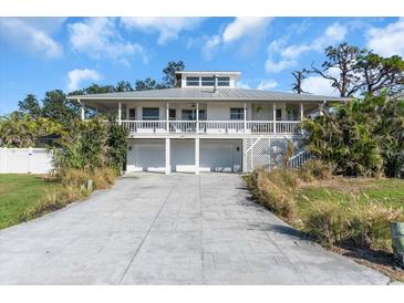 Two-story waterfront home featuring a metal roof, garage, and a charming wrap-around balcony at 2371 Scenic Dr, Venice, FL 34293