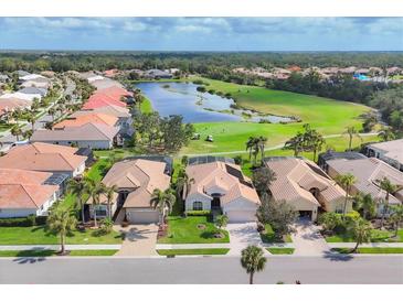 An aerial view of homes along the golf course with a lake in the community on a sunny day at 560 Misty Pine Dr, Venice, FL 34292
