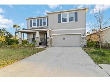 Two-story home features a neutral exterior, blue shutters, a two-car garage, and a front porch at 5767 Woodland Sage Dr, Sarasota, FL 34238