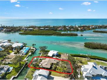 Stunning aerial view of waterfront home with boat dock and lush landscaping, nestled in a coastal community near the open ocean at 641 Bayshore Rd, Nokomis, FL 34275