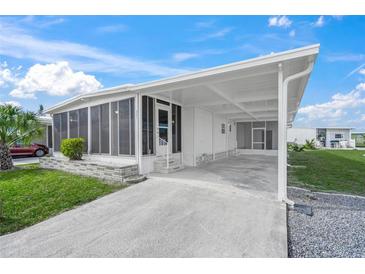 Bright exterior featuring a carport, screened porch, and well-maintained landscaping under a blue sky at 891 Grado Dr, Venice, FL 34285