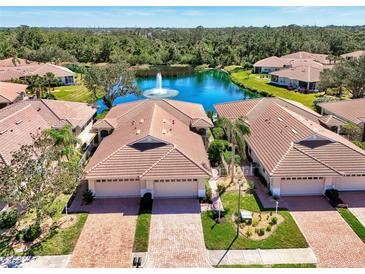 Stunning aerial view of a villa community with red tile roofs surrounding a tranquil lake and fountain at 1018 Yosemite Dr, Englewood, FL 34223