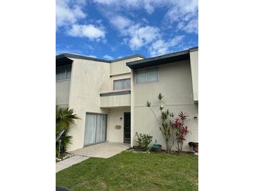 Two-story townhouse featuring a lawn with various green landscaping and a bright sky at 1190 Longfellow Way # 135C, Sarasota, FL 34243