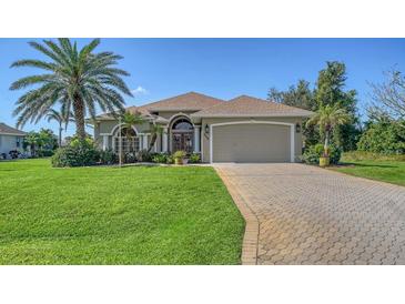 Charming single Gathering home featuring a paver driveway, manicured lawn and mature landscaping at 205 Antis Dr, Rotonda West, FL 33947