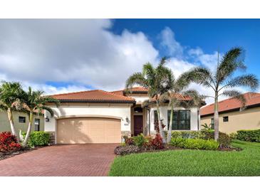 Charming single-story home featuring a red tile roof, beautiful landscaping and brick driveway at 23415 Waverly Cir, Venice, FL 34293