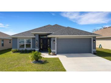 Charming single-story home showcasing a well-manicured lawn and a gray color scheme at 2572 Averland Loop, North Port, FL 34287