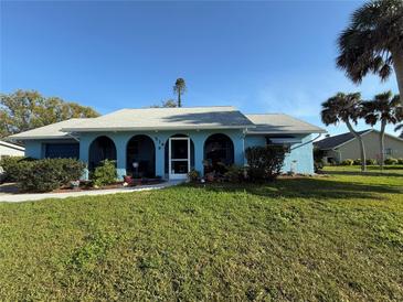 Charming blue home with arched porch, well-kept lawn, and mature palm trees create a cozy curb appeal at 519 Bellaire Dr, Venice, FL 34293