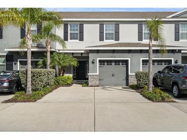 Charming townhome exterior with a two-car garage, featuring lush landscaping and palm trees at 6458 Baytown Dr, Sarasota, FL 34240