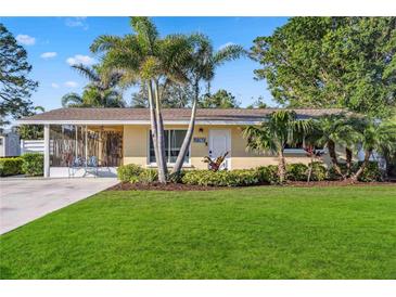 Well-maintained home with a green lawn, palm trees, and beautiful landscaping at 742 Golf Dr, Venice, FL 34285