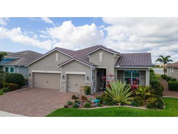 Charming single-Gathering home featuring a brick driveway, three-car garage and well-manicured landscaping at 11910 Alessandro Ln, Venice, FL 34293