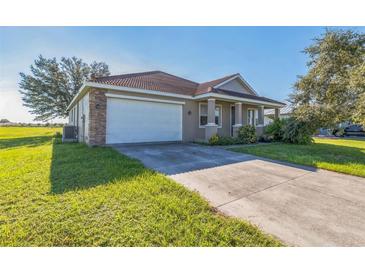 Tan single-story home featuring a two-car garage, tile roof and well maintained lawn at 17370 Cape Horn Blvd, Punta Gorda, FL 33955