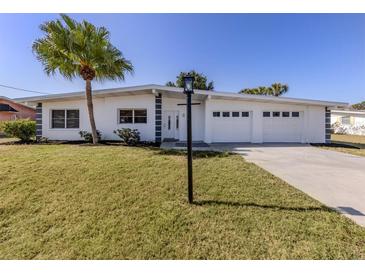 Charming single-story home featuring a well-manicured lawn, a large palm tree, and a three-car garage at 506 Buena Vista Dr, Nokomis, FL 34275